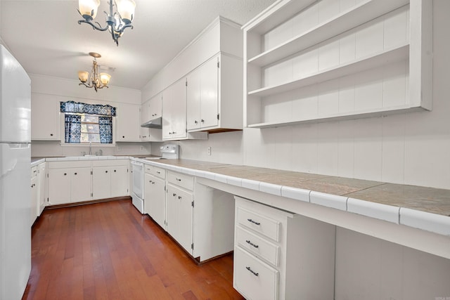 kitchen with white cabinetry, a notable chandelier, tile countertops, decorative light fixtures, and white appliances
