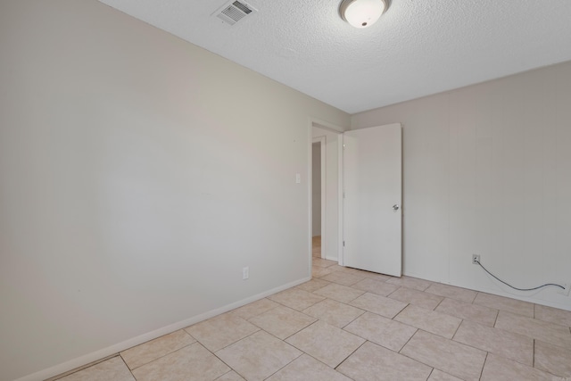 tiled empty room with a textured ceiling