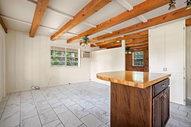 kitchen featuring a center island, an AC wall unit, ceiling fan, beam ceiling, and butcher block counters