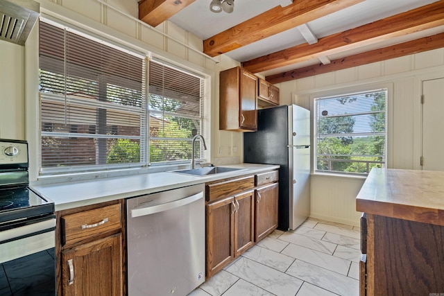 kitchen featuring beamed ceiling, a healthy amount of sunlight, sink, and stainless steel appliances