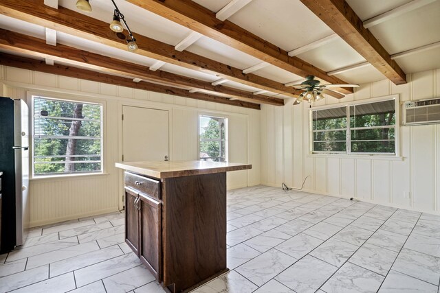 kitchen featuring stainless steel refrigerator, ceiling fan, beamed ceiling, dark brown cabinets, and a kitchen island
