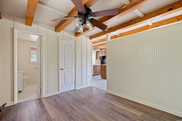 spare room with beamed ceiling, ceiling fan, and wood-type flooring
