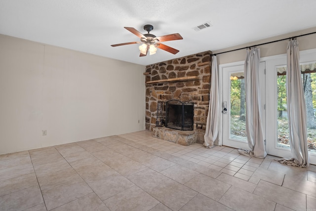 unfurnished living room featuring a fireplace, a textured ceiling, ceiling fan, and light tile patterned flooring