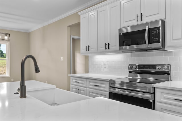 kitchen with white cabinets, stainless steel appliances, crown molding, and sink