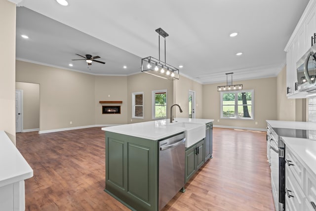 kitchen featuring a center island with sink, light hardwood / wood-style flooring, ceiling fan, appliances with stainless steel finishes, and white cabinetry