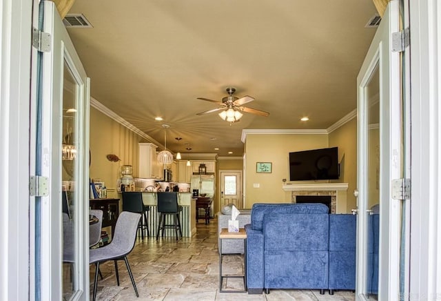 living room with ceiling fan and ornamental molding