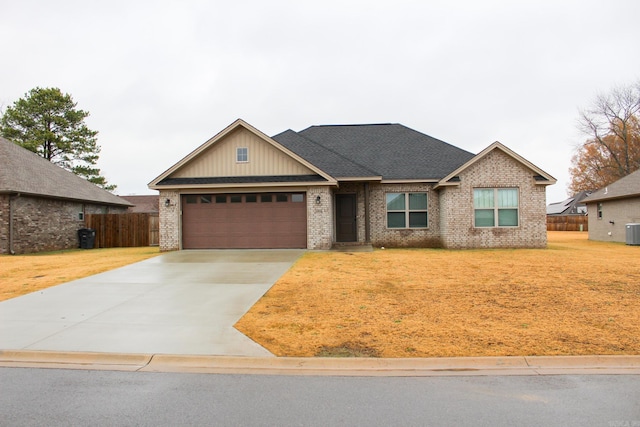 view of front of property featuring a garage, cooling unit, and a front lawn