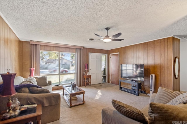 carpeted living room featuring a textured ceiling, ceiling fan, and wooden walls