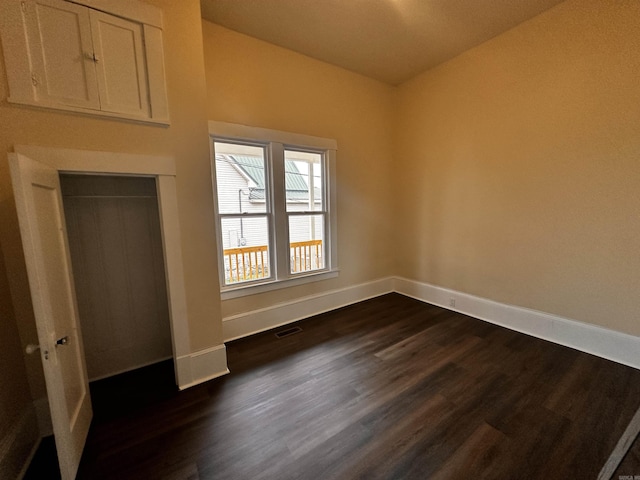 unfurnished bedroom featuring a closet and dark wood-type flooring