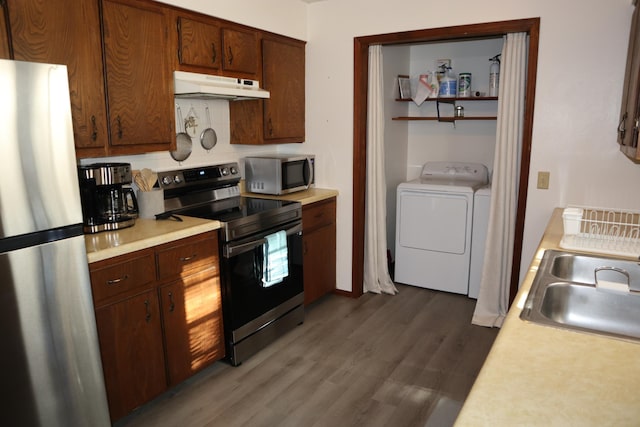 kitchen with washer and clothes dryer, dark hardwood / wood-style floors, sink, and appliances with stainless steel finishes