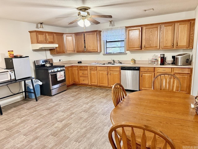 kitchen with ceiling fan, sink, stainless steel appliances, light hardwood / wood-style floors, and a textured ceiling