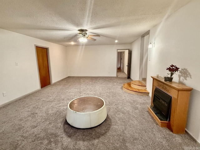 sitting room featuring ceiling fan, carpet floors, and a textured ceiling