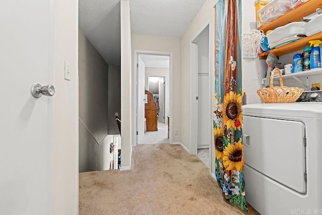 laundry room featuring light carpet, washer / dryer, and a textured ceiling