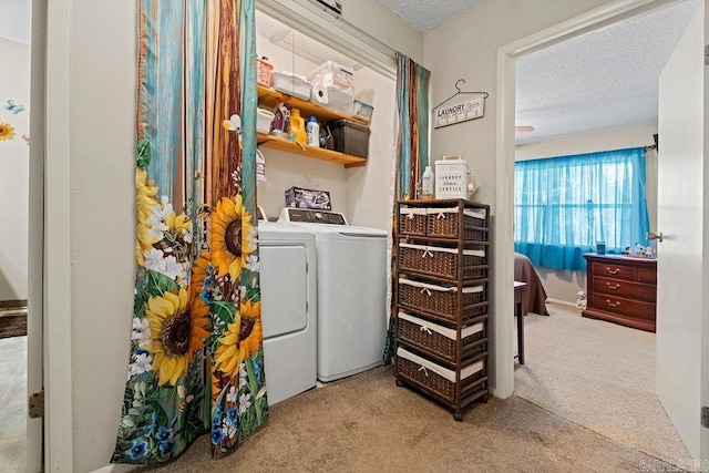 washroom featuring light carpet, washer and clothes dryer, and a textured ceiling