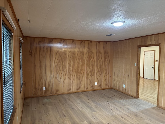 empty room with wooden walls and light hardwood / wood-style floors