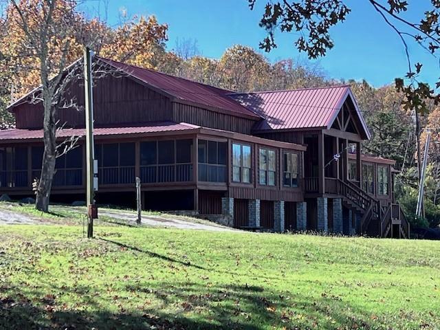 rear view of property featuring a yard and a sunroom