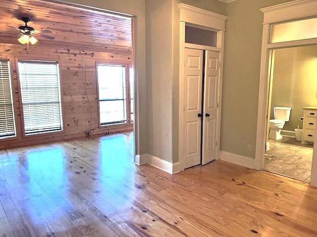 interior space with light hardwood / wood-style flooring, ceiling fan, and wooden walls