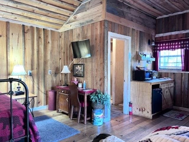 bedroom featuring light hardwood / wood-style floors, vaulted ceiling, and wooden walls