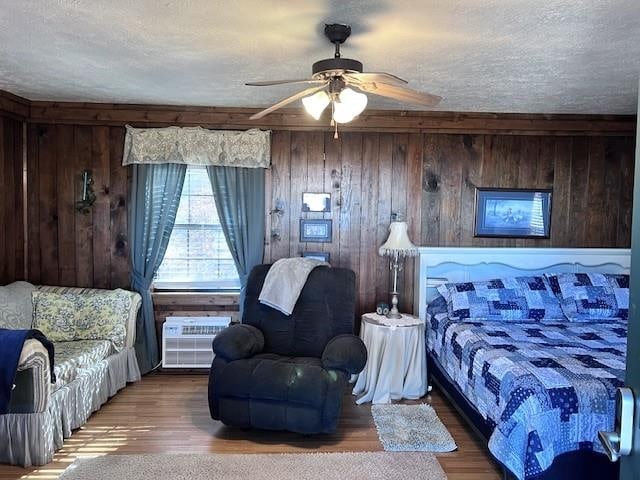 bedroom with hardwood / wood-style floors, ceiling fan, wood walls, and a textured ceiling