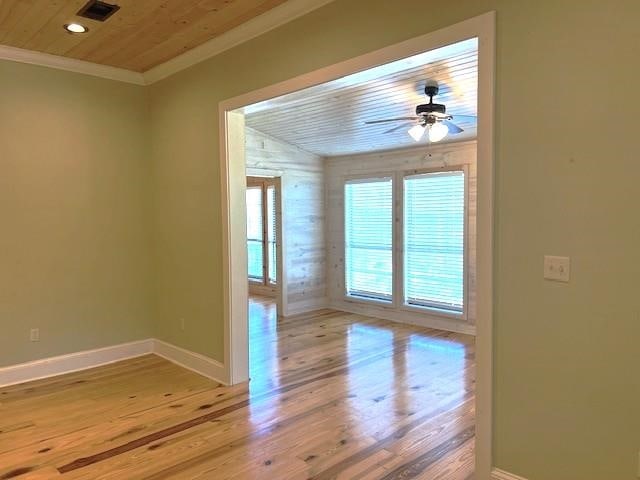 unfurnished room with ceiling fan, wooden ceiling, wood walls, and light wood-type flooring