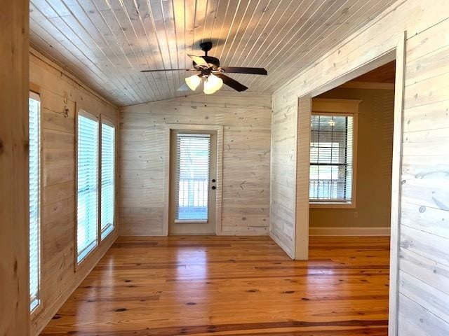 doorway featuring plenty of natural light, wood walls, wooden ceiling, and vaulted ceiling