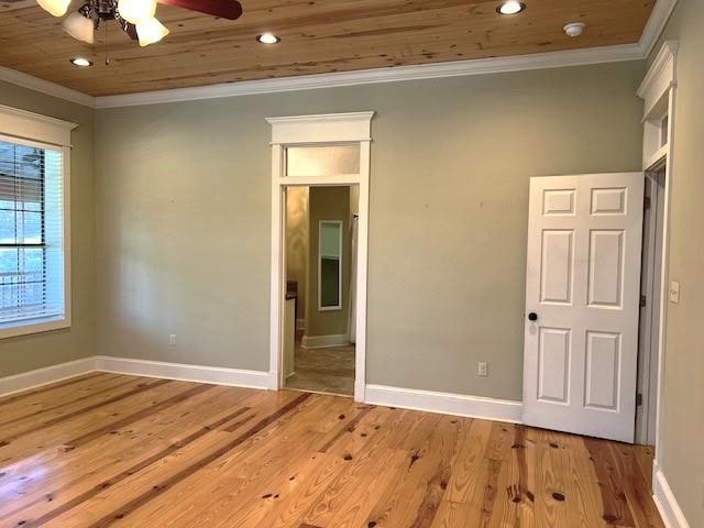 empty room with ceiling fan, light hardwood / wood-style floors, wood ceiling, and ornamental molding