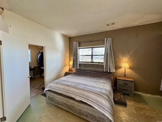 bedroom with a spacious closet, a closet, concrete floors, and a textured ceiling