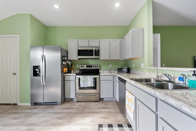 kitchen with gray cabinetry, sink, stainless steel appliances, and light wood-type flooring