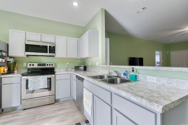 kitchen featuring sink, stainless steel appliances, kitchen peninsula, light hardwood / wood-style floors, and white cabinets