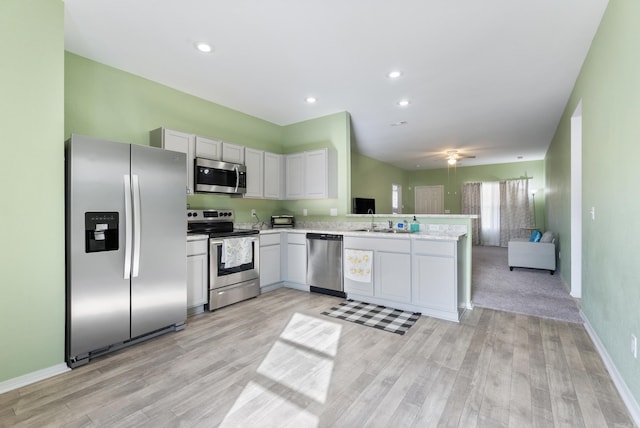 kitchen featuring kitchen peninsula, stainless steel appliances, light hardwood / wood-style flooring, and sink