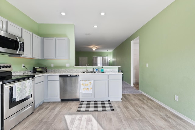 kitchen with sink, kitchen peninsula, stainless steel appliances, and light hardwood / wood-style flooring