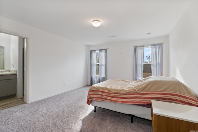 carpeted bedroom with ensuite bath and sink