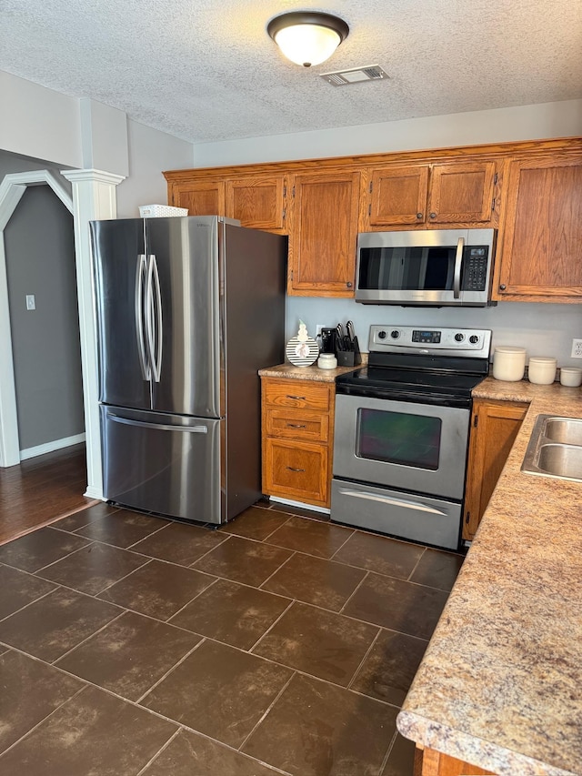 kitchen with a textured ceiling, stainless steel appliances, and sink