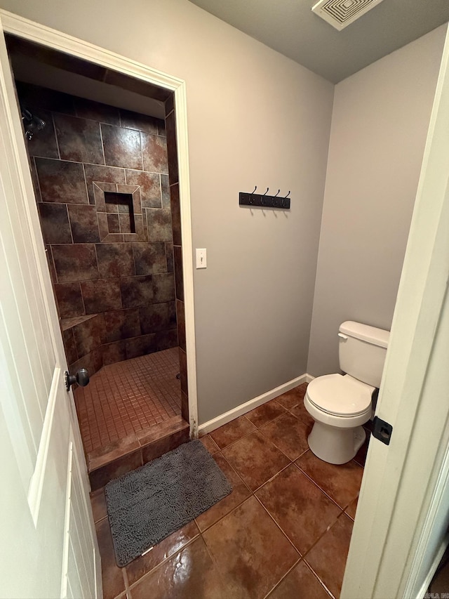 bathroom featuring tiled shower, tile patterned floors, and toilet