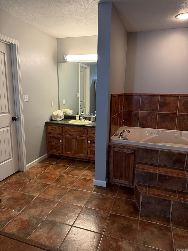 bathroom featuring vanity, a textured ceiling, and tiled bath