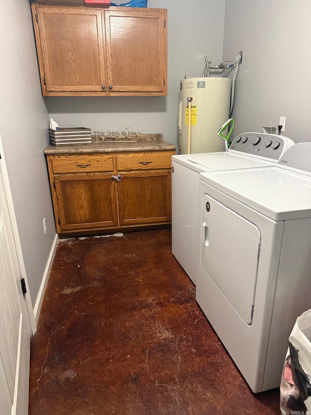 laundry room featuring washer and dryer, electric water heater, and cabinets