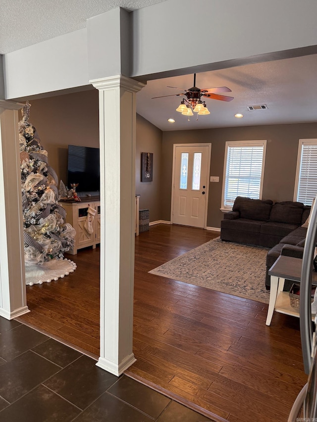 foyer entrance with decorative columns, ceiling fan, dark wood-type flooring, and a textured ceiling