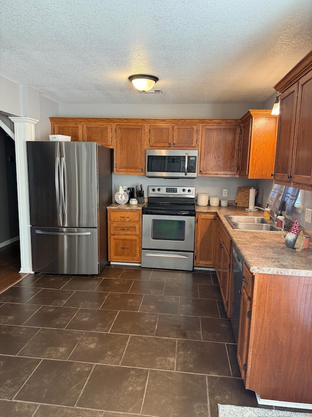 kitchen with a textured ceiling, sink, and appliances with stainless steel finishes