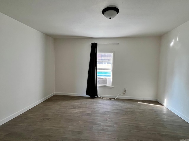 empty room featuring cooling unit and dark wood-type flooring