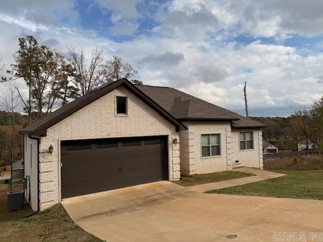 view of front of property with central AC, a front lawn, and a garage