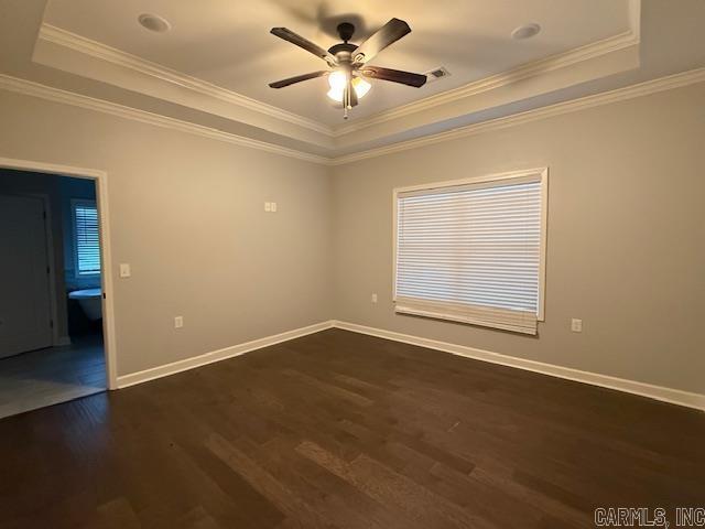 unfurnished room featuring dark hardwood / wood-style flooring, a raised ceiling, and ornamental molding