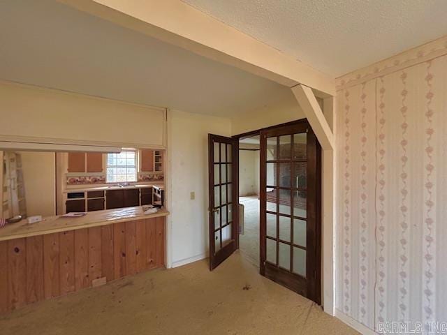 kitchen with light carpet, french doors, and a textured ceiling