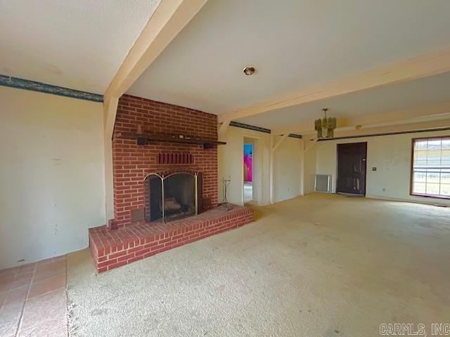 unfurnished living room with a fireplace, beam ceiling, and carpet flooring