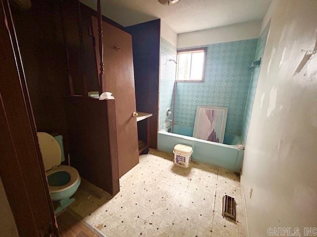 bathroom featuring tiled shower / bath combo and toilet