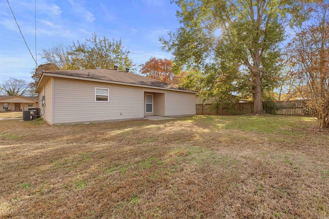 back of property with a yard and central AC