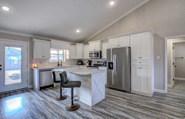 kitchen with appliances with stainless steel finishes, light hardwood / wood-style flooring, white cabinetry, and crown molding