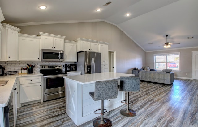 kitchen featuring white cabinets, a kitchen island, lofted ceiling, and appliances with stainless steel finishes