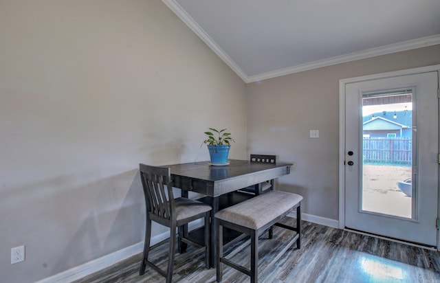 dining space with dark hardwood / wood-style floors, crown molding, and vaulted ceiling