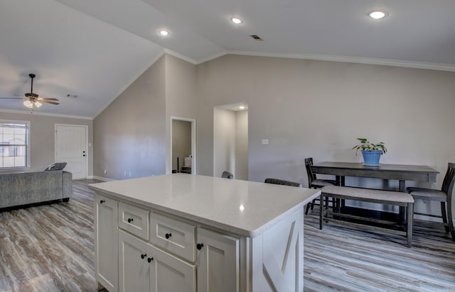 kitchen featuring light wood-type flooring, ornamental molding, vaulted ceiling, ceiling fan, and white cabinets