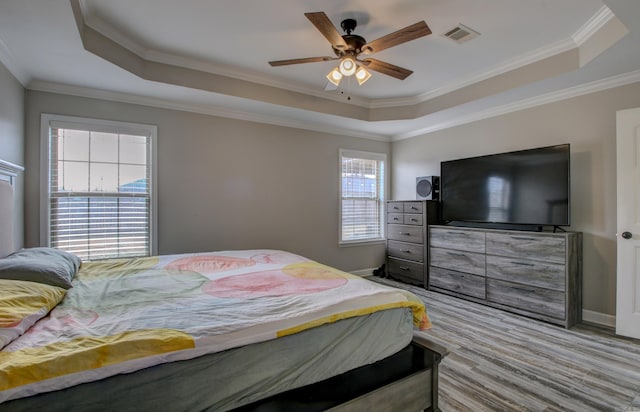 bedroom featuring a raised ceiling, multiple windows, ceiling fan, and crown molding